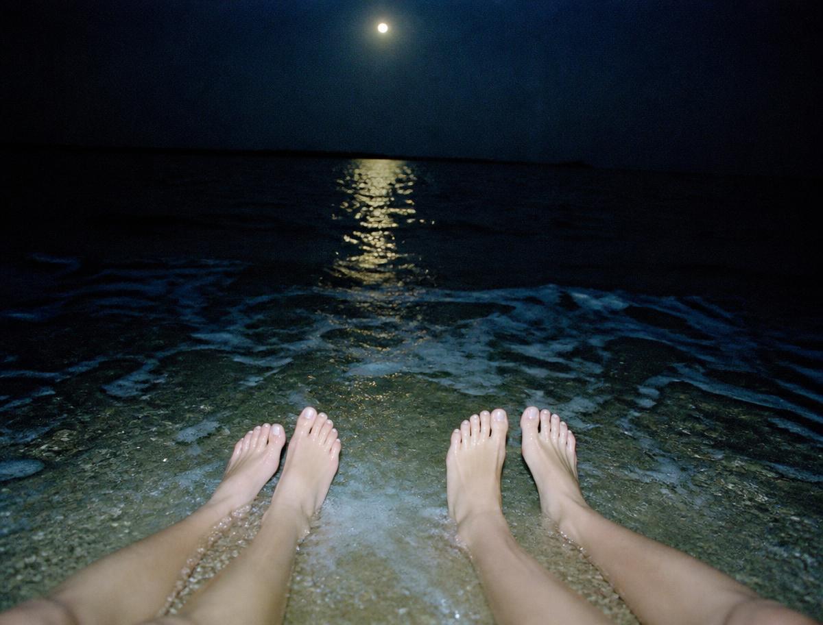 Pés dentro do mar, à noite